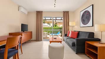 Hotelkamer met een eethoek, een bank, een televisie, een lamp en uitzicht op het omliggende landschap.