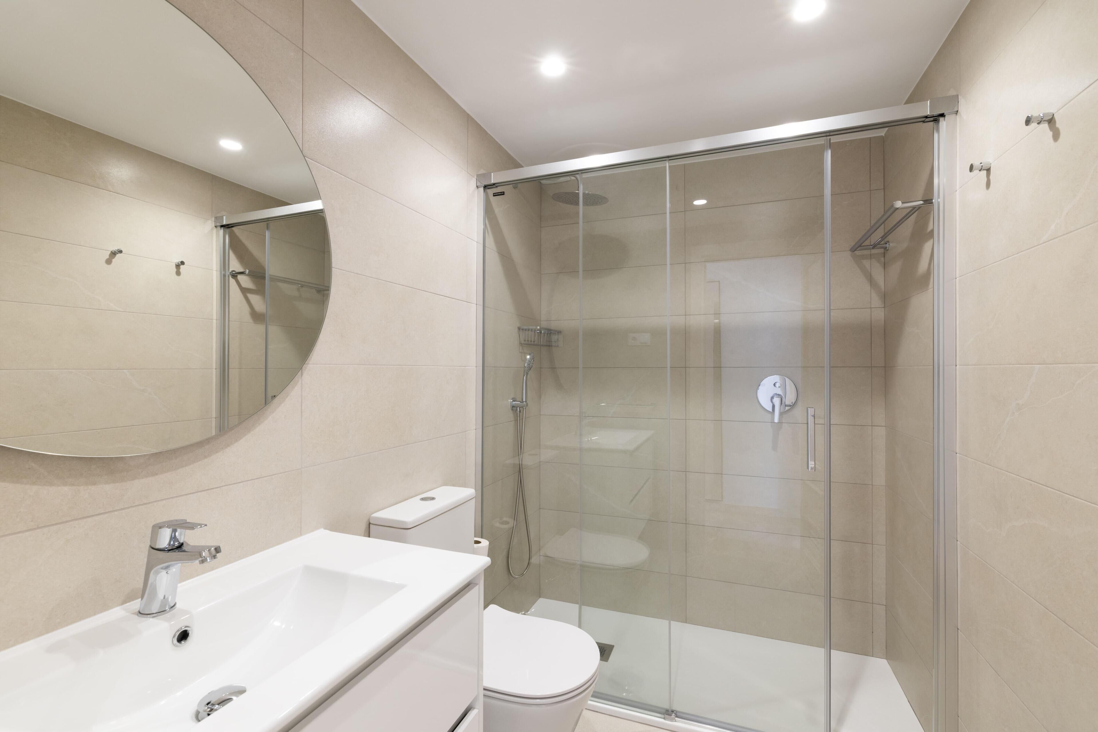 A modern bathroom with a glass-enclosed shower, a white sink, and a toilet.