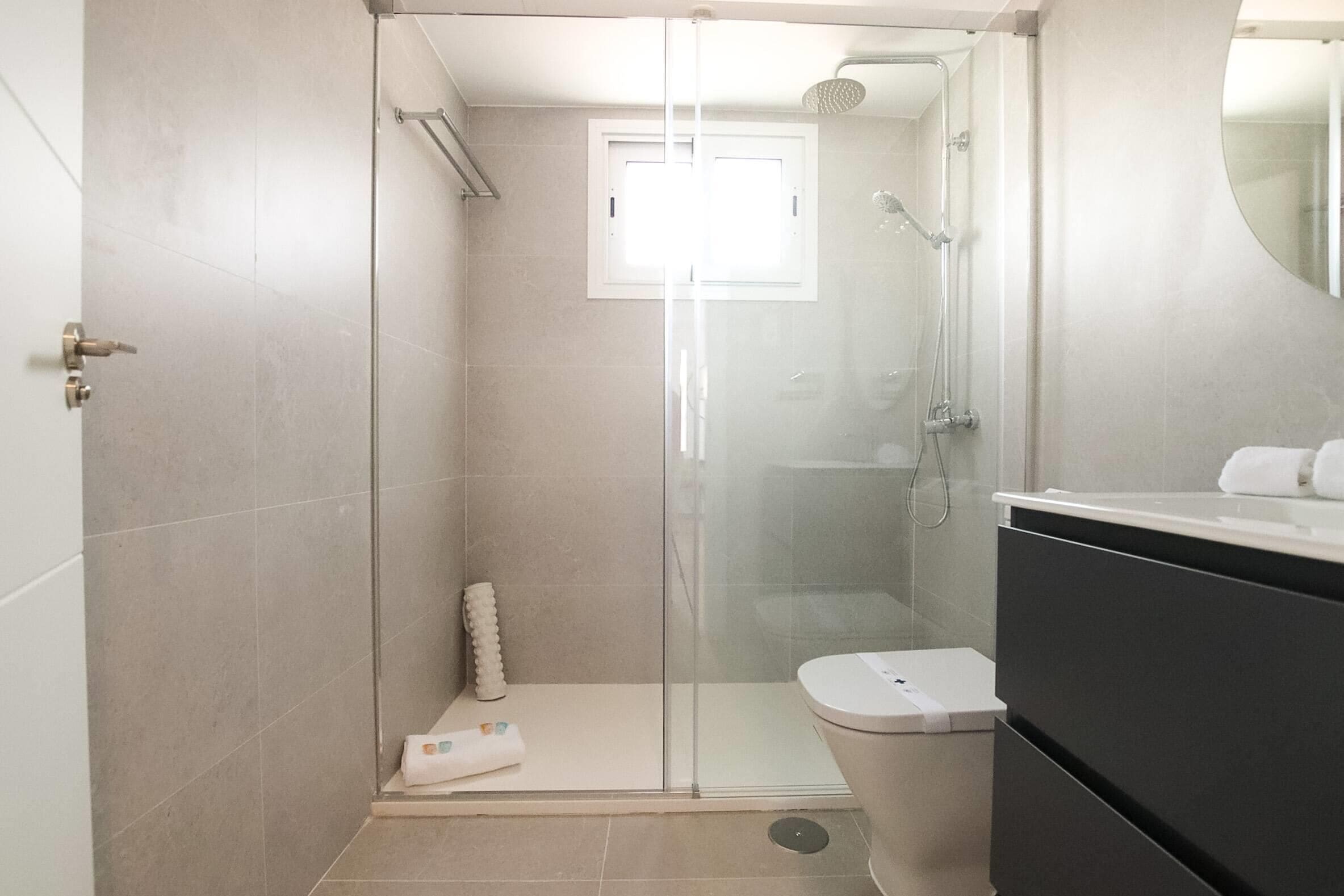 A modern bathroom with a glass-enclosed shower, a toilet, and a vanity with a mirror.