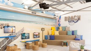 Habitación con temática playera, que incluye un mural, tablas de surf y un sofá con cojines estampados.