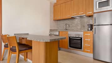 Una cucina moderna con mobili in legno, un piano di lavoro in granito, forno integrato e frigorifero in acciaio inossidabile.