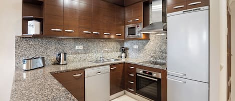 A modern kitchen with granite countertops, stainless steel appliances, and wooden cabinetry.