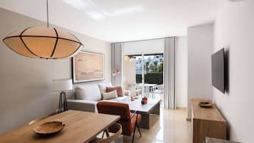 Una sala de estar moderna con comedor, ventanas amplias y un televisor de pantalla plana montado en la pared.