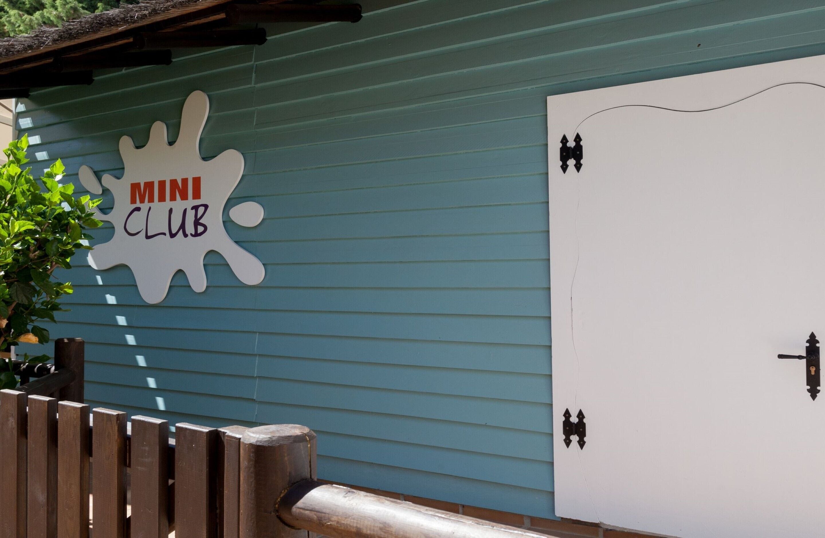 En byggnadsfasad med en skylt som visar texten ”MINI CLUB” och en dörr med ett nyckelhål.