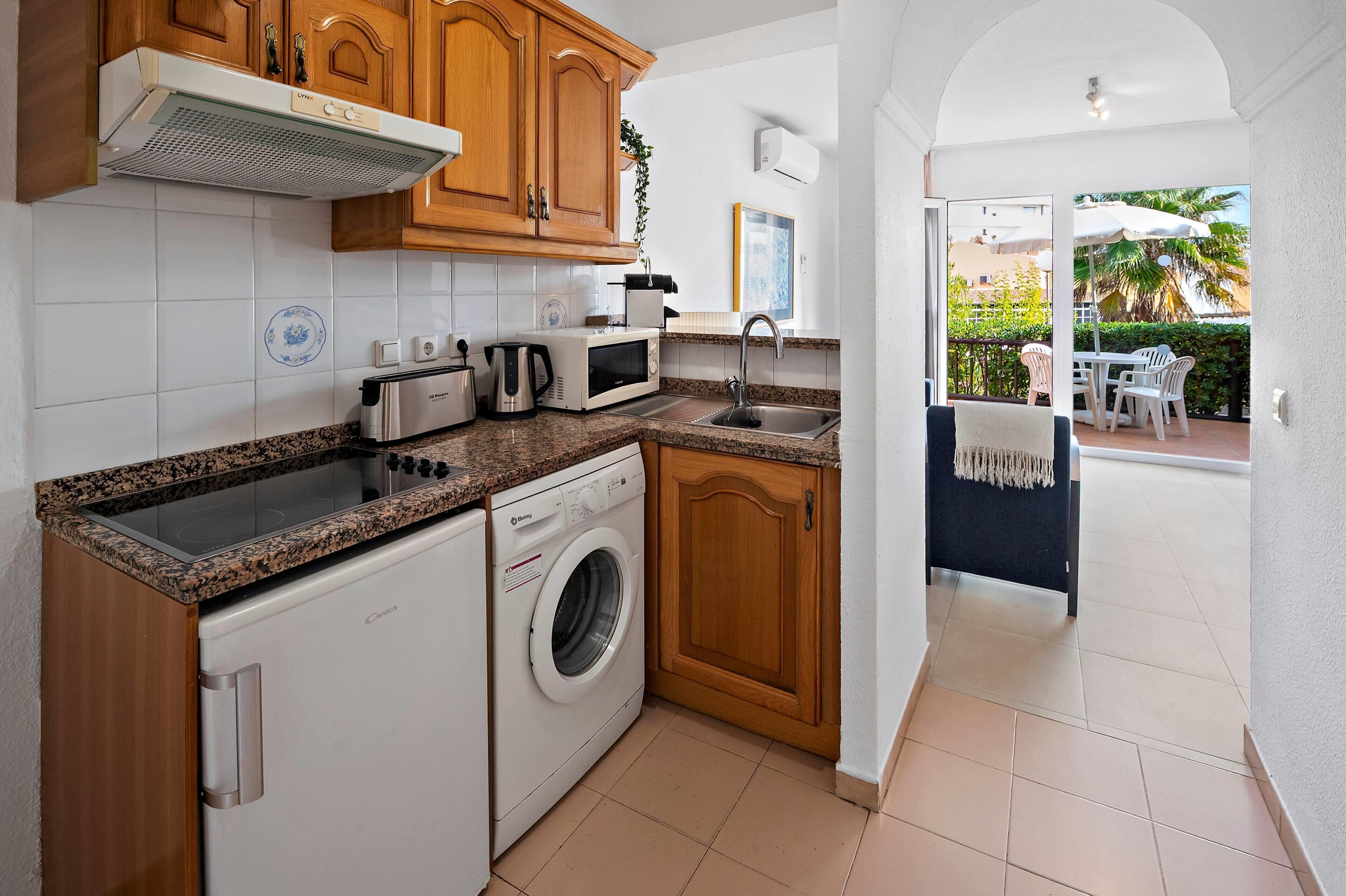 A compact kitchen with a washing machine, microwave, and a sink.