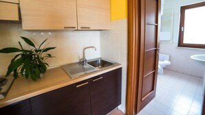 A kitchen with wooden cabinets, a sink, and a potted plant. - La Maison Jolie (Fiumicino)