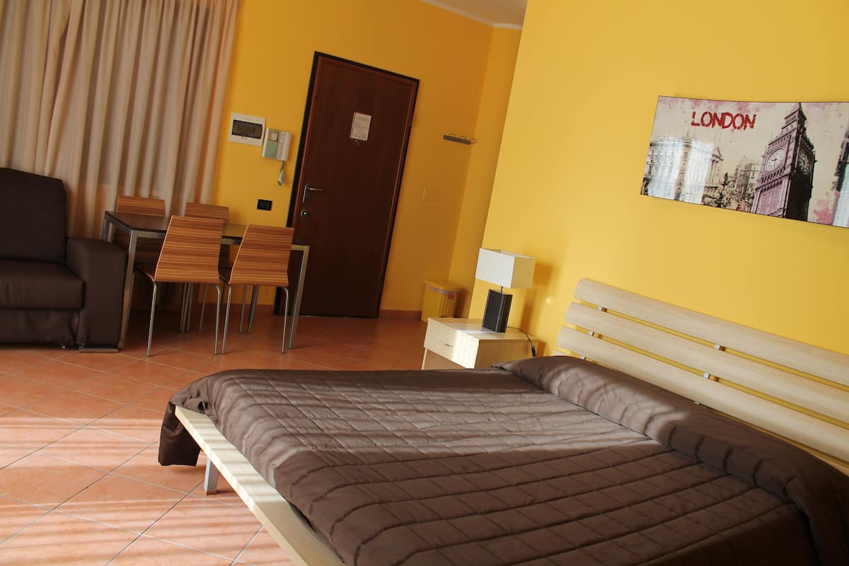 Ein Hotelzimmer mit einem Bett, einem Schreibtisch, einem Stuhl, einer Couch und einem Bild von London an der Wand.