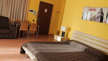 Ein Hotelzimmer mit einem Bett, einem Schreibtisch, einem Stuhl, einer Couch und einem Bild von London an der Wand.