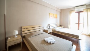 A hotel room with a large bed, a smaller bed, a nightstand with a lamp, a bedside table, and a painting on the wall. - La Maison Jolie (Fiumicino)