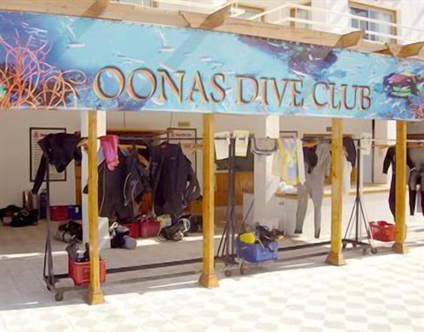 A covered area with a sign reading "Oonas Dive Club" and various diving equipment and gear.