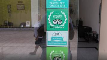 Una puerta de vidrio con múltiples placas de premios de TripAdvisor, incluyendo 'Ganador 2014' y 'Elección de Viajeros 2015'.