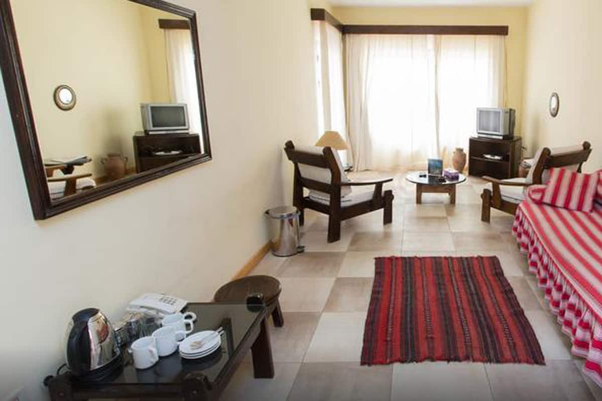 A compact living room with a sofa, chairs, a coffee table, a TV, and a dining table with chairs.