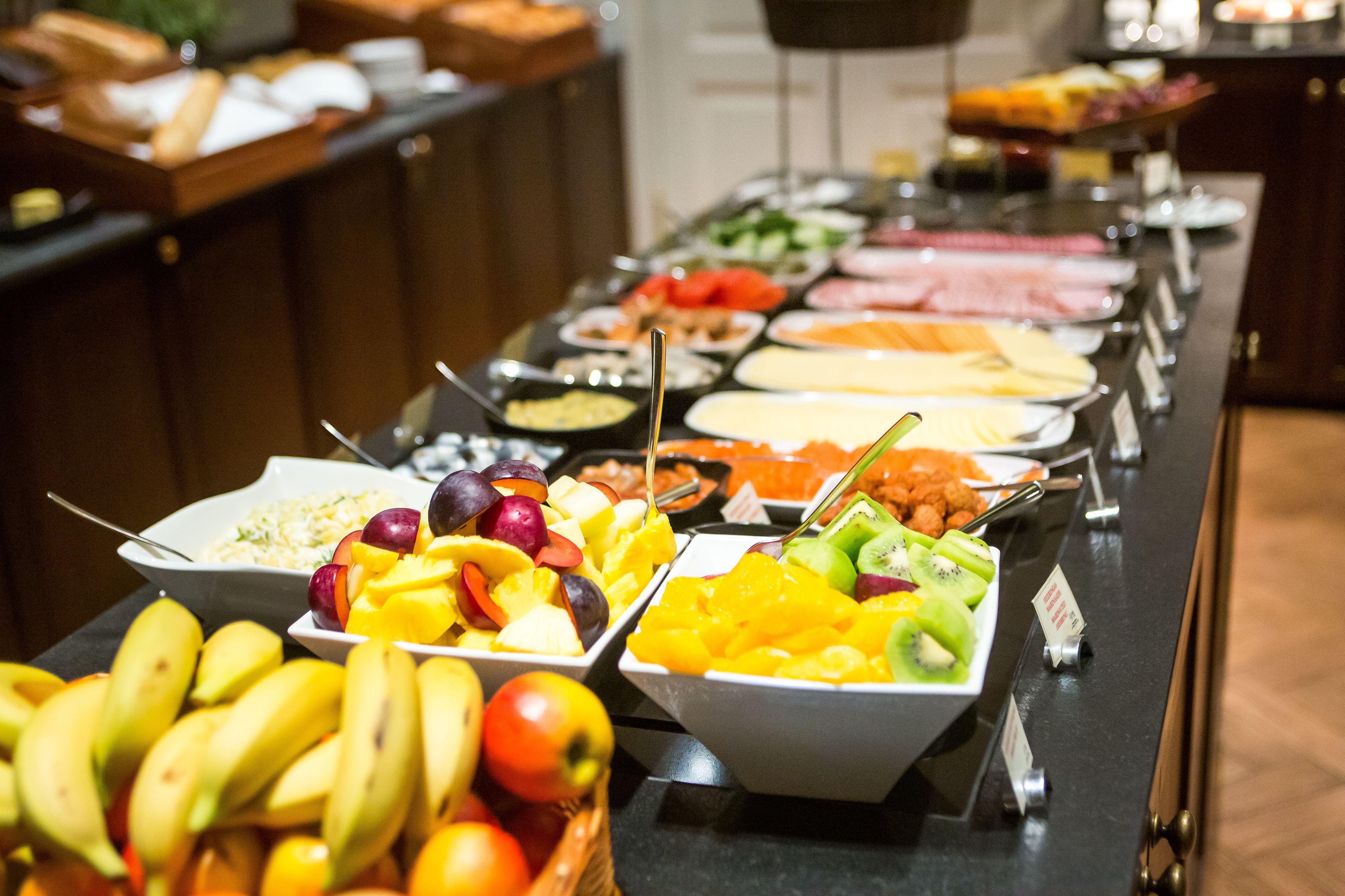 Ein Buffet mit verschiedenen Speisen, darunter Obst, Gemüse und Fleisch.