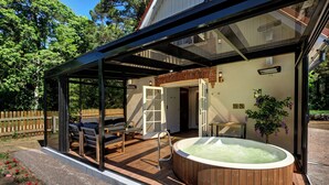 A glass-enclosed outdoor area with a hot tub, seating, and a wooden deck. - Vihula Manor Country Club and Spa (Vihula)