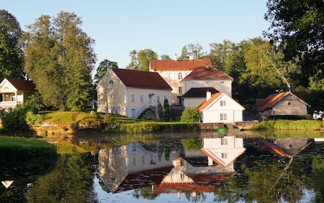 A lakeside property with multiple buildings, a dock, and a reflection in the water.