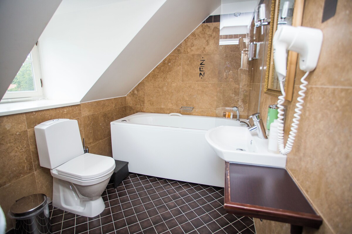 A modern bathroom with a toilet, bathtub, and sink.