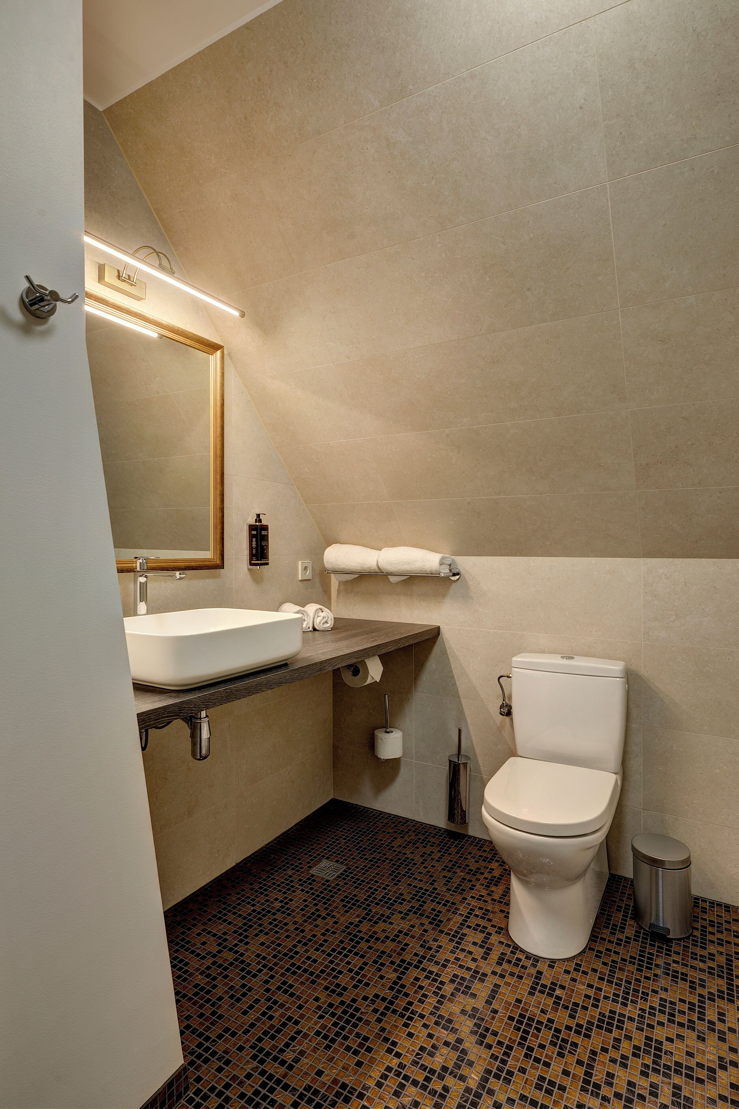 A bathroom with a white sink, mirror, and toilet.