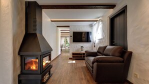 A modern living room with a wood-burning stove, a leather sofa, and a flat-screen TV mounted on the wall. - Vihula Manor Country Club and Spa (Vihula)