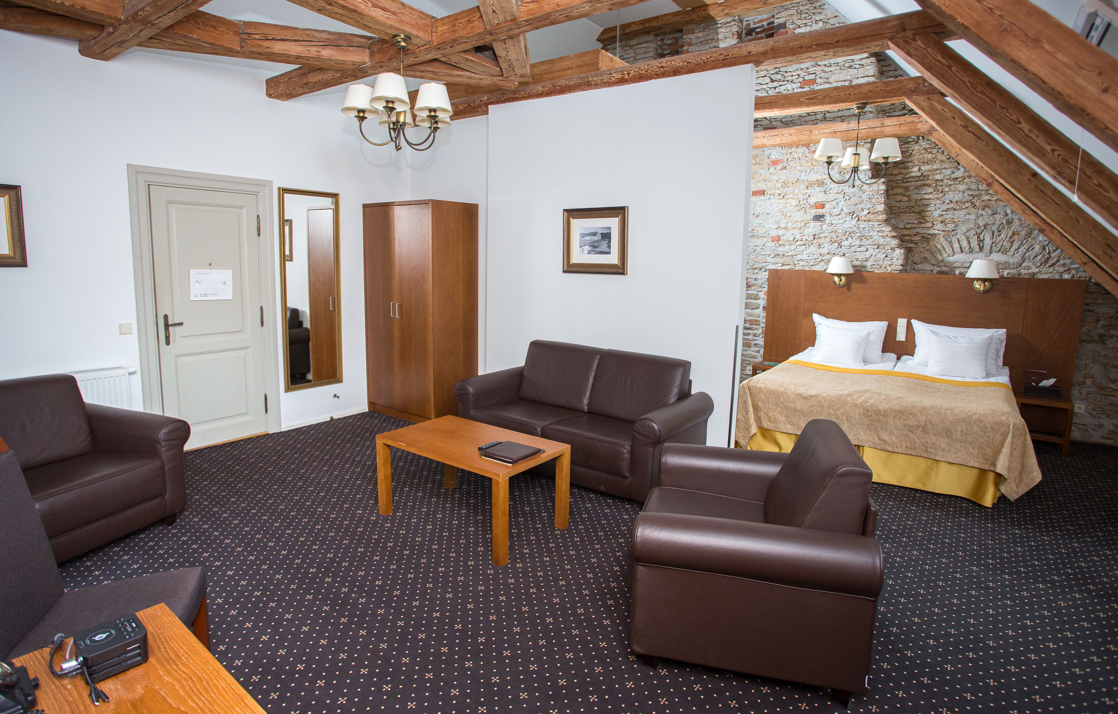 Una camera d'albergo con un letto, due divani, un tavolino da caffè e una scrivania in legno.