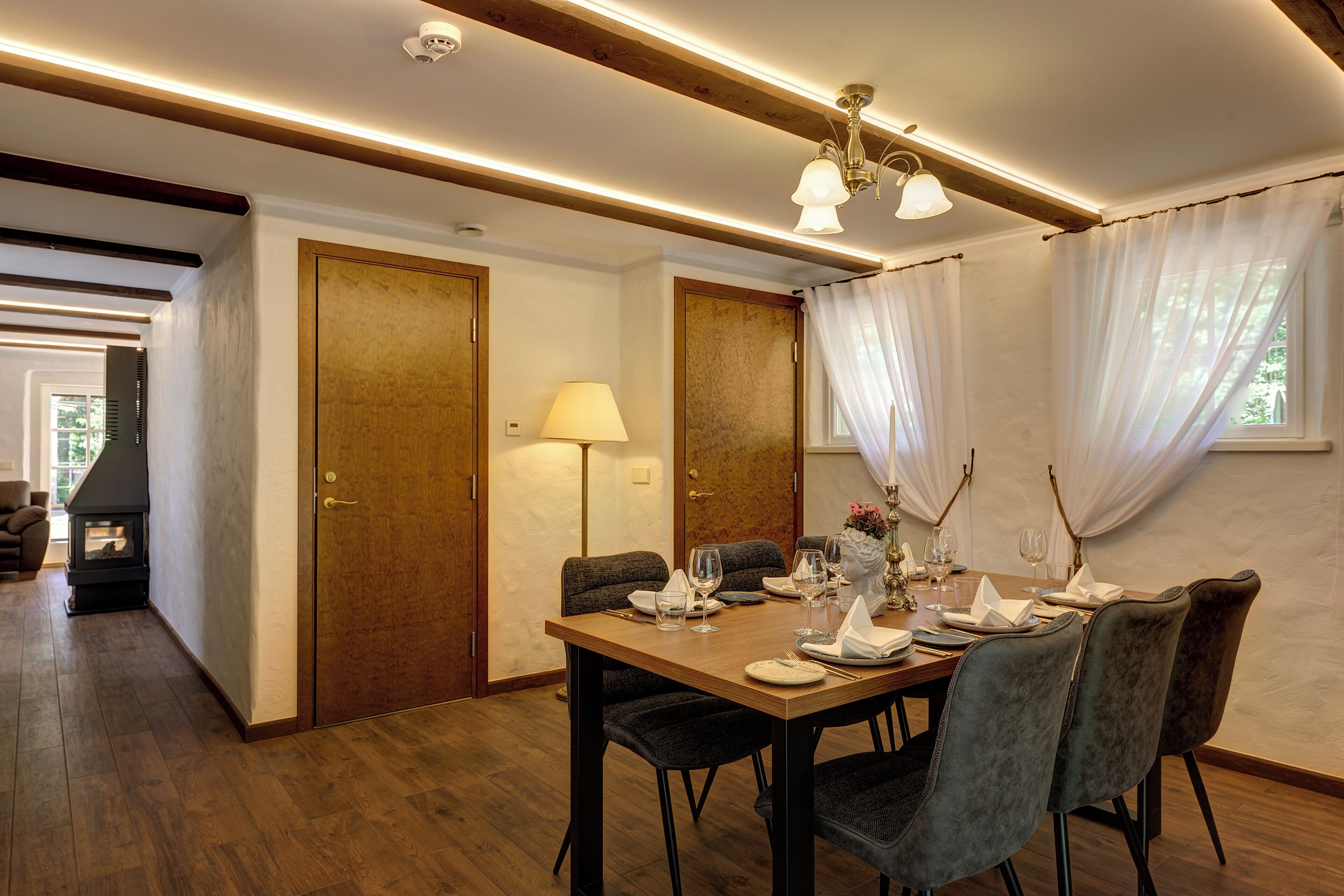 A dining area with a wooden table set for four, surrounded by upholstered chairs.