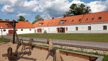 A traditional building with a red-tiled roof and white walls, featuring a stable with wooden horseshoes and a swing set.
