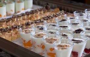 Una presentación de postres con diversas opciones cremosas en vasos, algunas cubiertas de galletas desmenuzadas y otras con trozos de fruta.