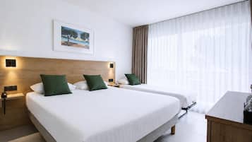 Habitación de hotel con dos camas, cabecero de madera, un cuadro y un amplio ventanal con cortinas.