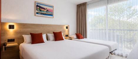A hotel room with two beds, a large window with curtains, a painting on the wall, and a balcony.