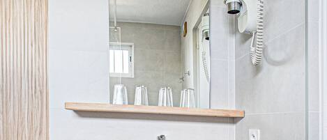 A modern bathroom with a wooden vanity, a large mirror, a white sink, and a towel rack.