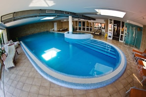 Una piscina techada, sillones reclinables de piscina