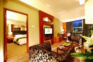 A hotel room with a bed, a television, a sofa, a coffee table, and a view of the city through a window. - Empark Grand Hotel Xian (Xi'an)