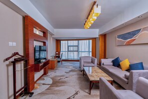 A modern hotel room with a sofa, armchairs, a TV, and a large window. - Empark Grand Hotel Xian (Xi'an)