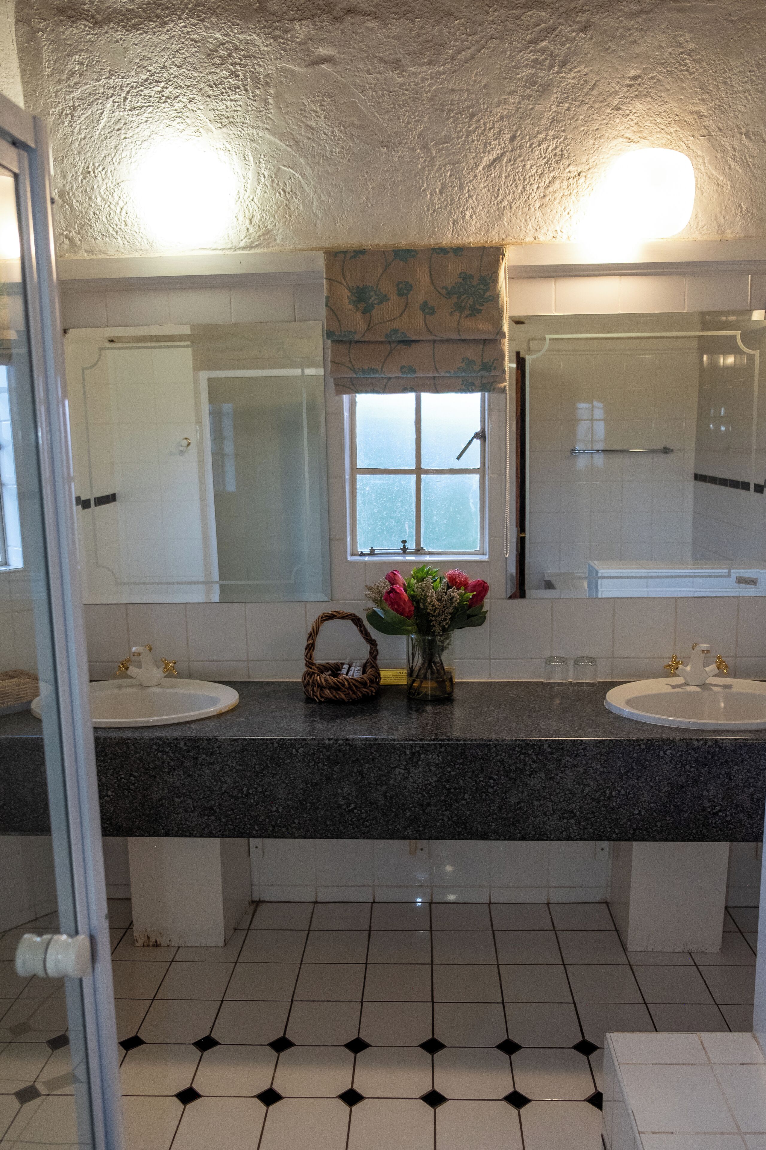 A bathroom with two sinks, a large mirror, and a shower.