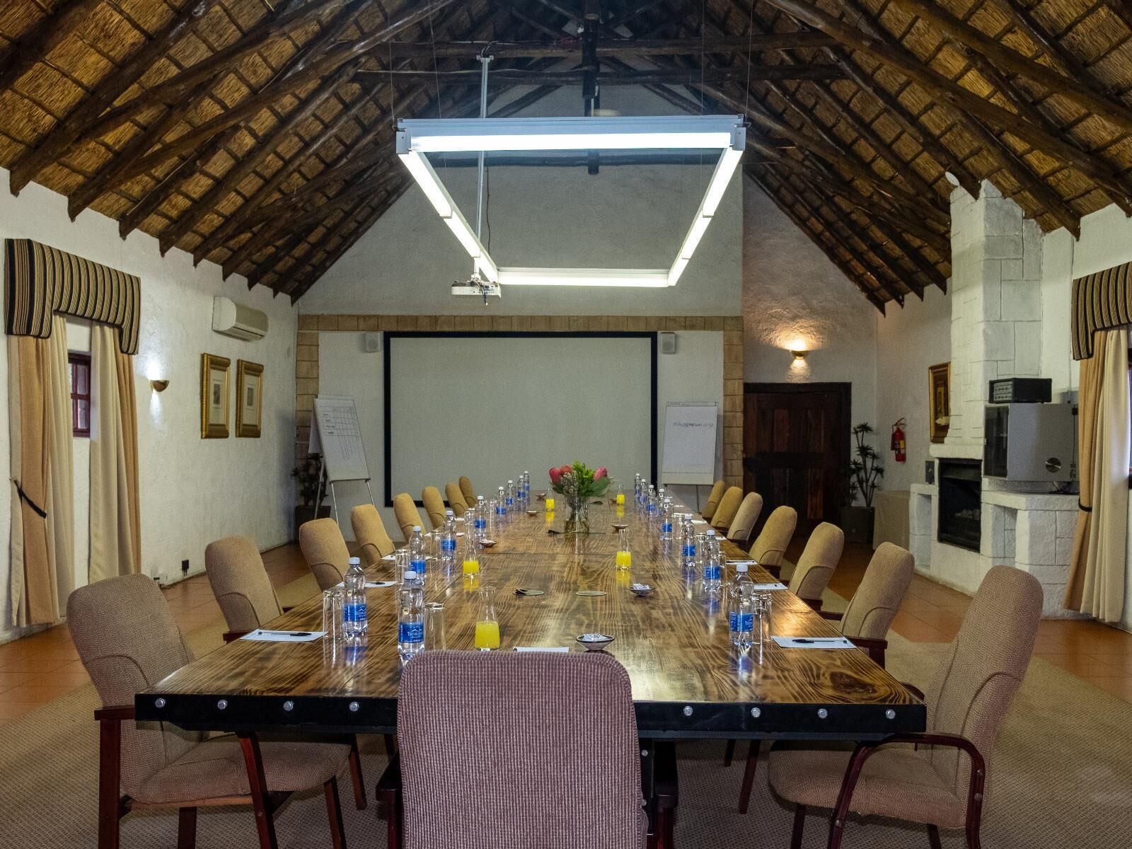 A conference room with a long table, chairs, and a projector screen.