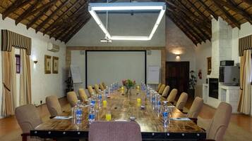 A conference room with a long table, chairs, and a projector screen.