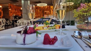 A dining table with a dessert platter, two glasses of white wine, and a bowl of salad. - Evenia Rossello (Barcelona)