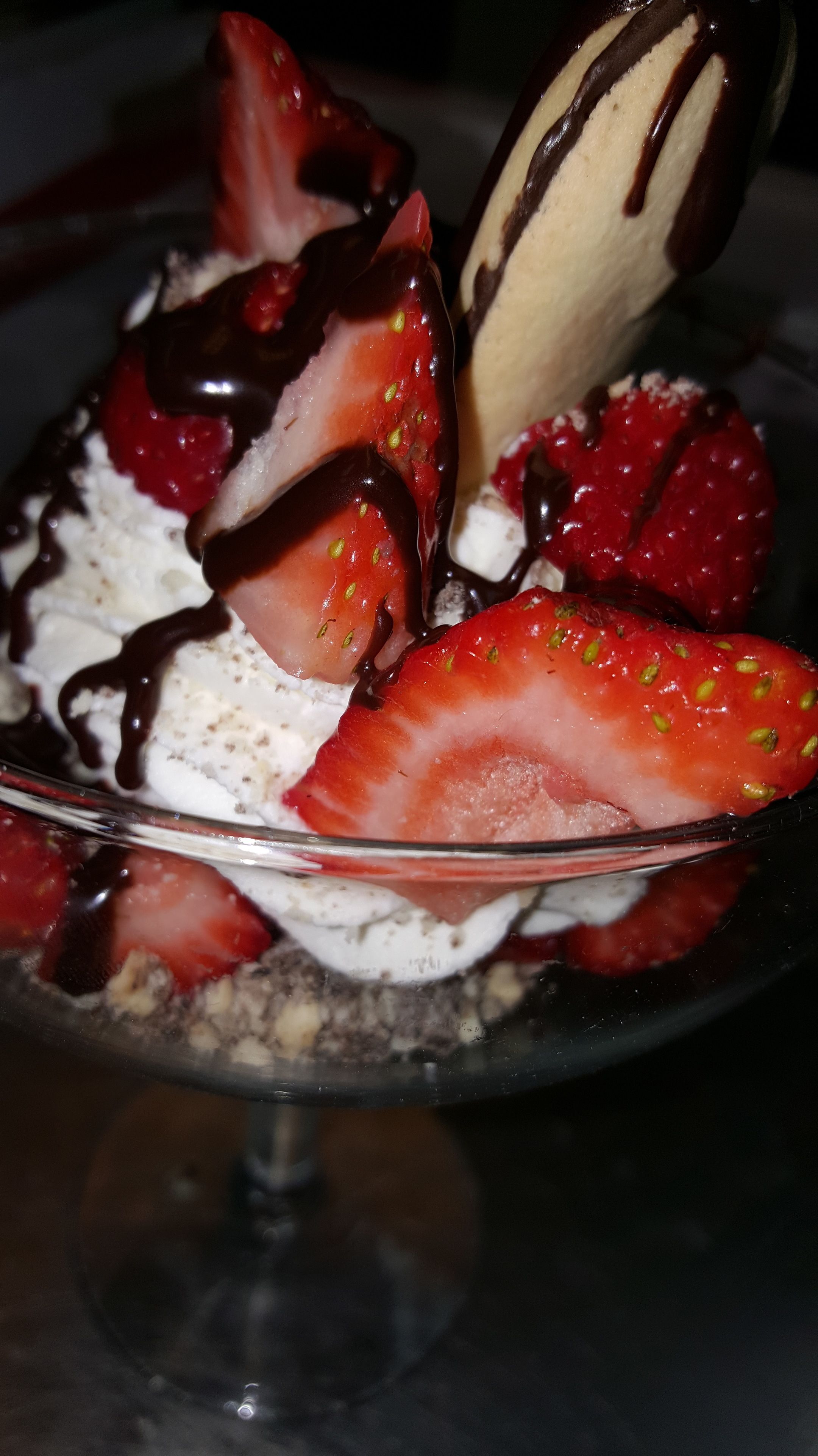 Een dessert met aardbeien, slagroom en chocoladesaus.