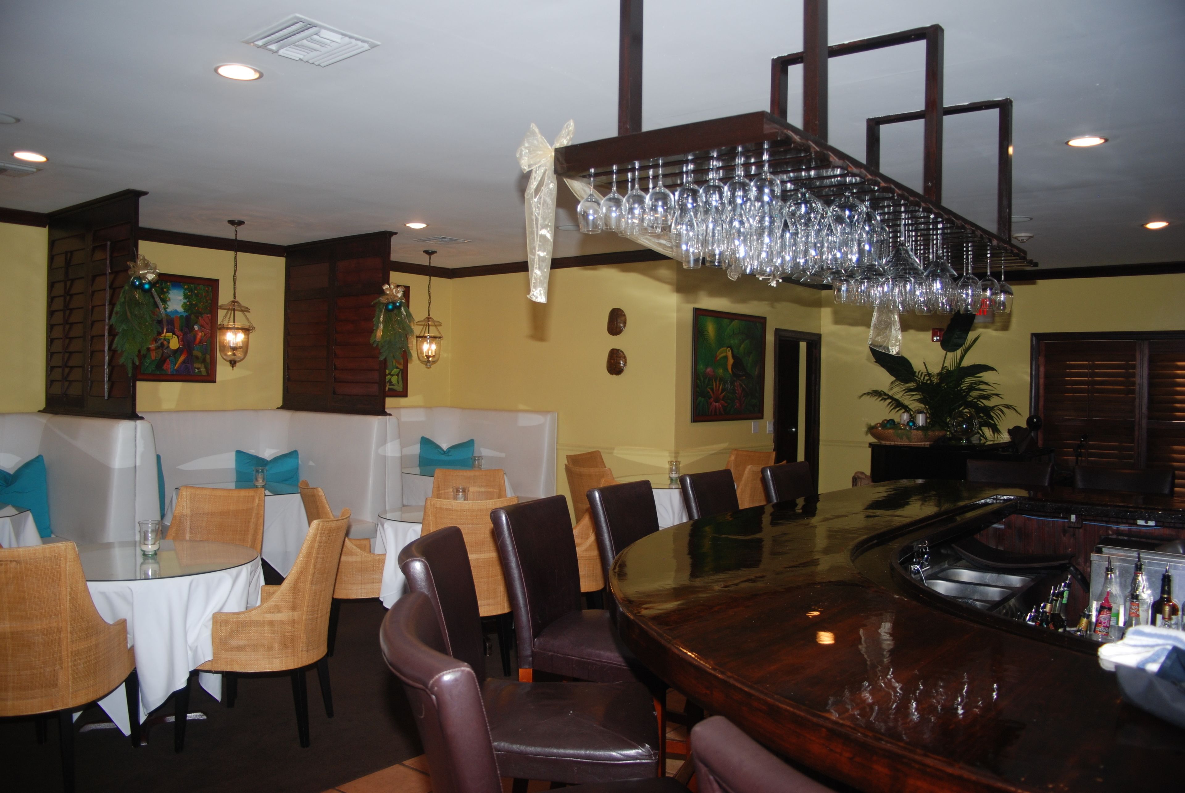 Een restaurant met ronde tafels, rieten stoelen en een bar met een houten toonbank.