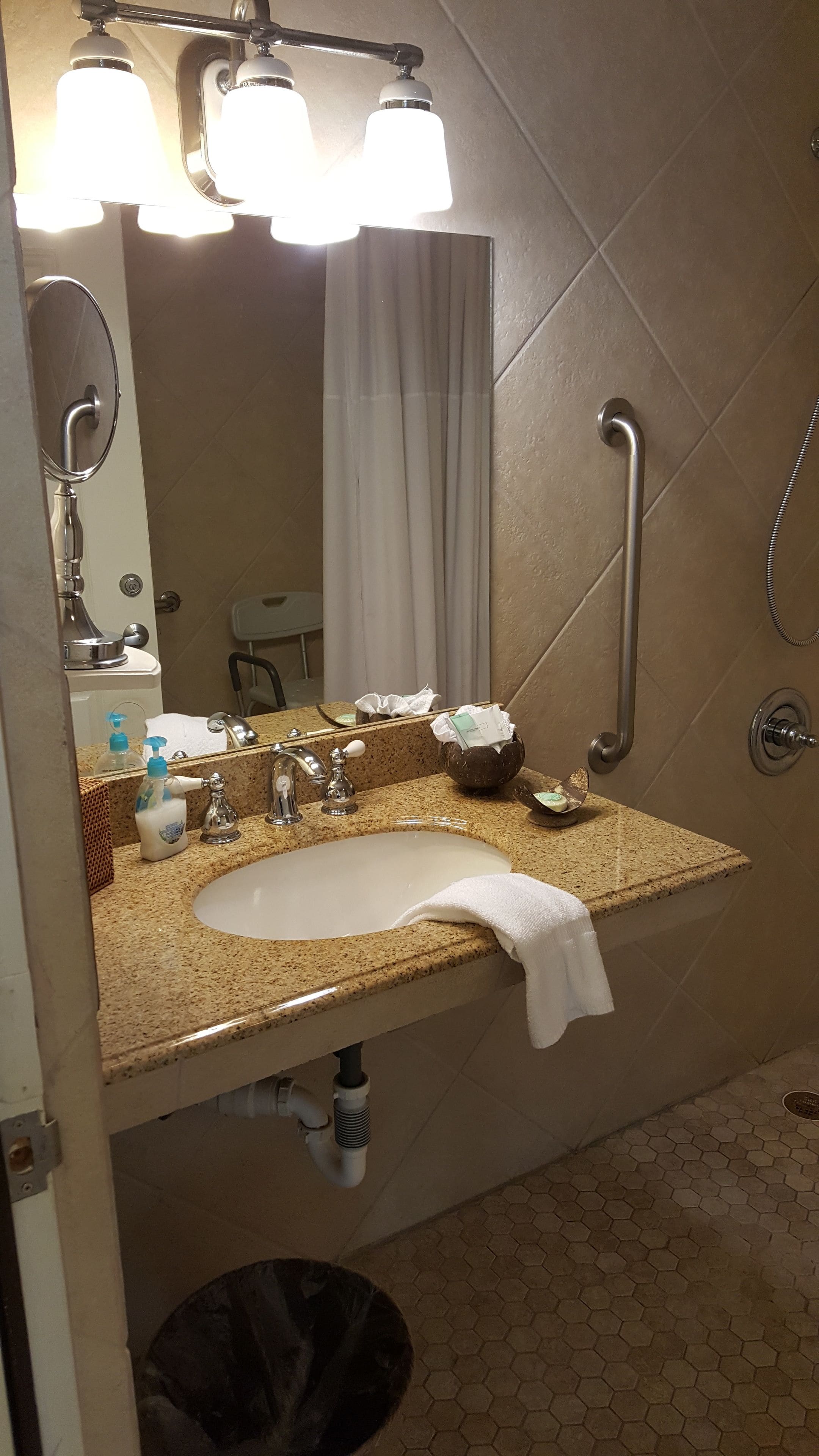 Une salle de bain avec un lavabo, un miroir, une serviette et une douche.