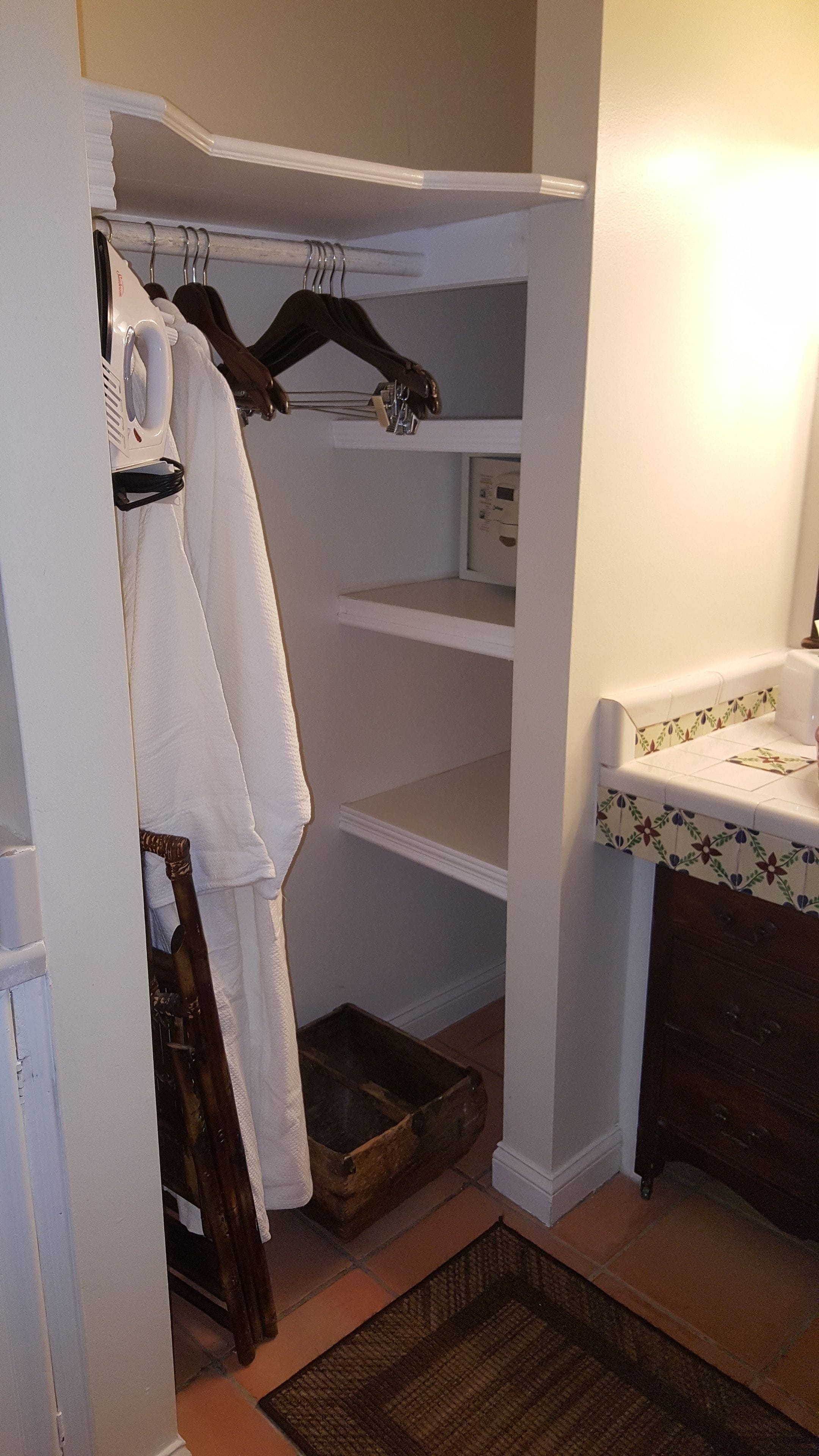A walk-in closet with shelves, a hanging rack, and a small sink area.