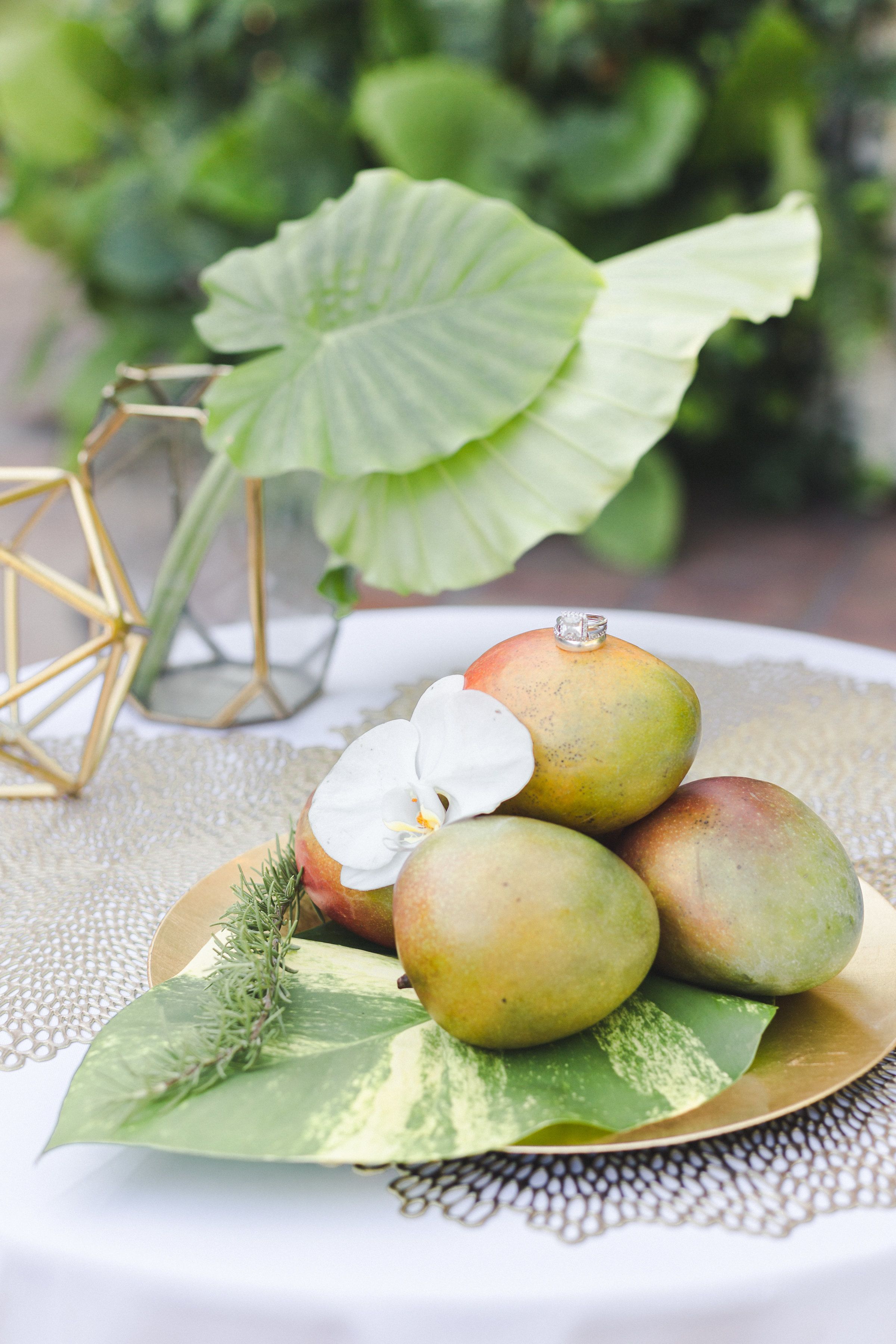 A plate with mangoes and a white orchid on a table with a lace tablecloth.