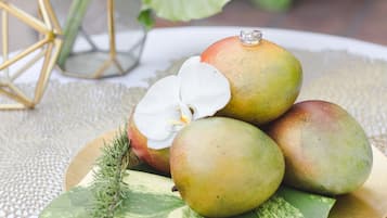 A plate with mangoes and a white orchid on a table with a lace tablecloth.
