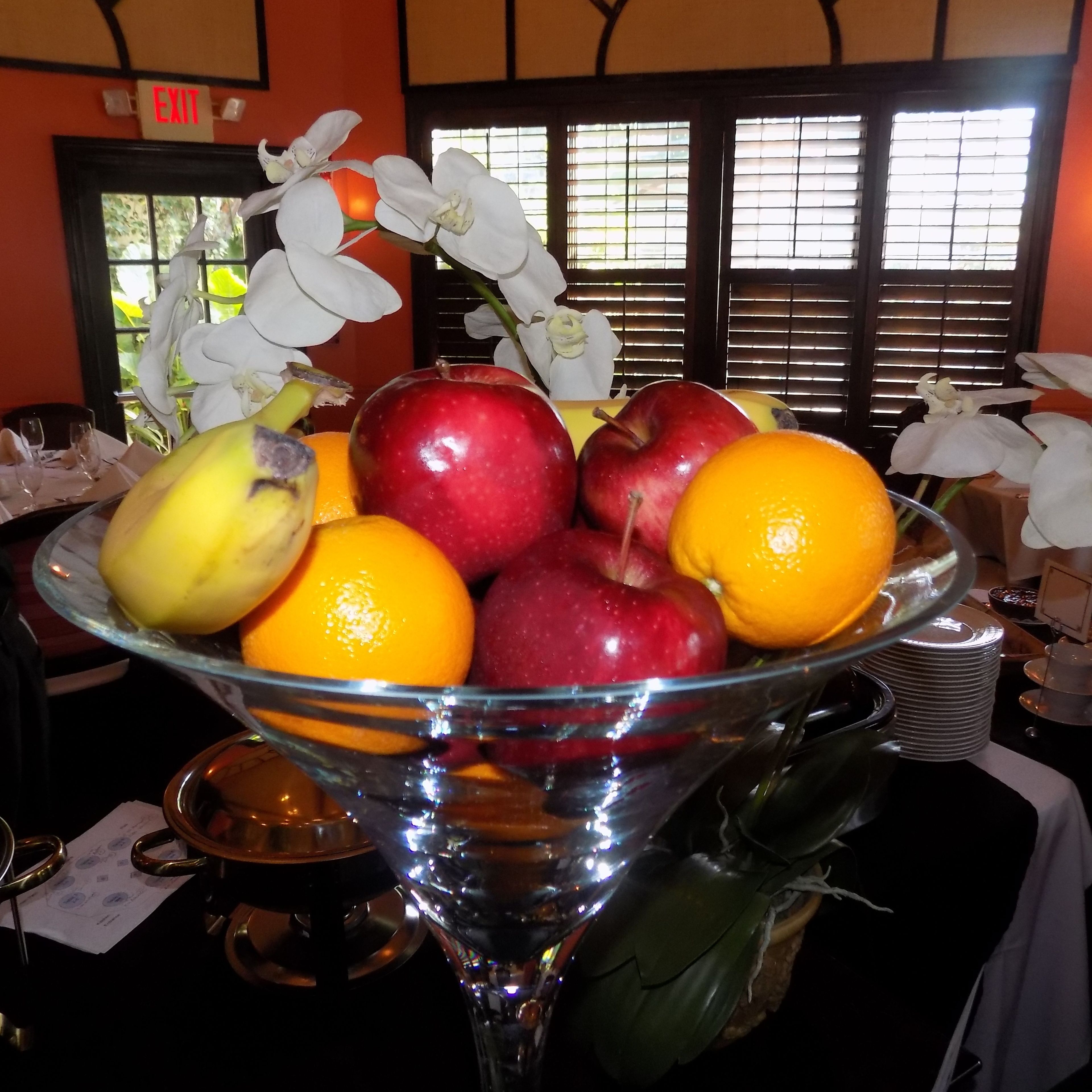 A fruit bowl with apples, oranges, and bananas on a table.