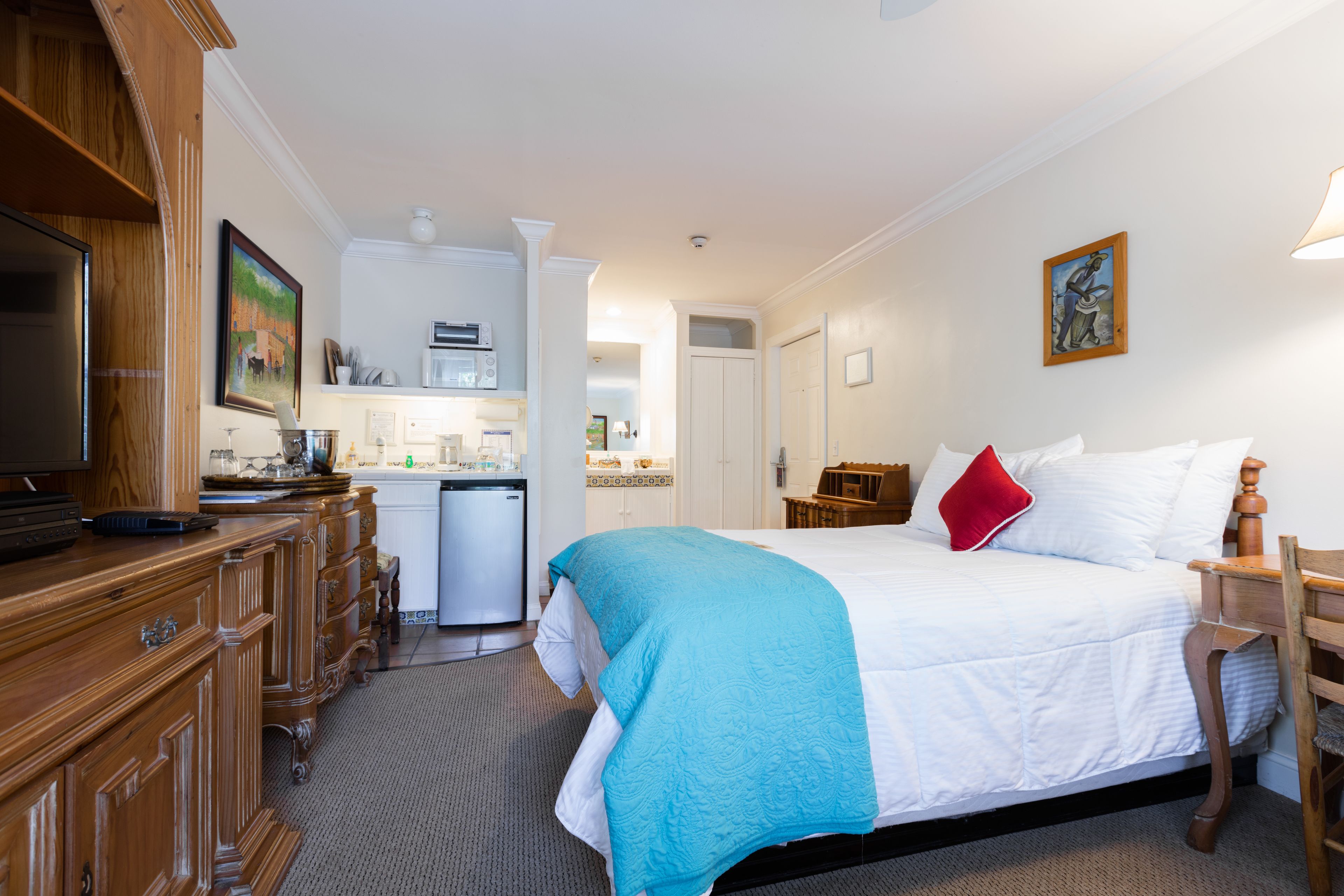 Een hotelkamer met een groot bed, een houten dressoir en een kitchenette.