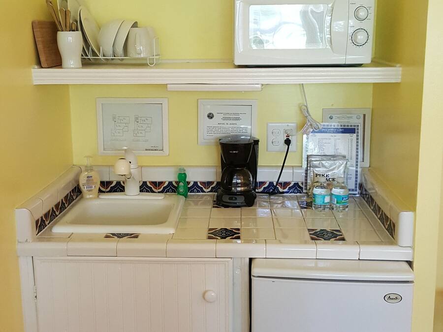 Eine kompakte Küche mit Mikrowelle, Kaffeemaschine und einem kleinen Kühlschrank.