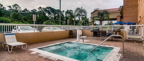 Una piscina al aire libre con cerca blanca, sillas de descanso y mesas.