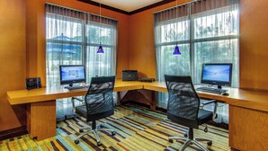 Una sala de conferencias con dos escritorios, cada uno con un ordenador y una silla, ventanas amplias con cortinas y un escritorio de madera.