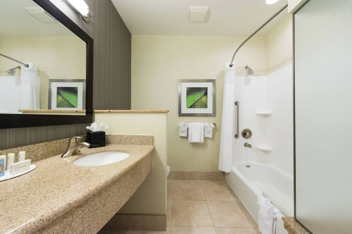 A bathroom with a sink, mirror, and shower.