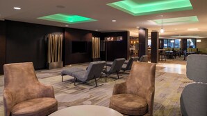A modern lounge area with leather armchairs, a flat-screen TV, and a bar area in the background.