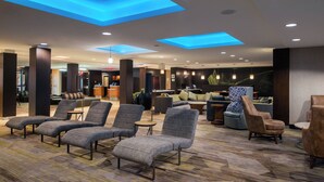 A hotel lobby with multiple seating areas, a reception desk, and a bar area.